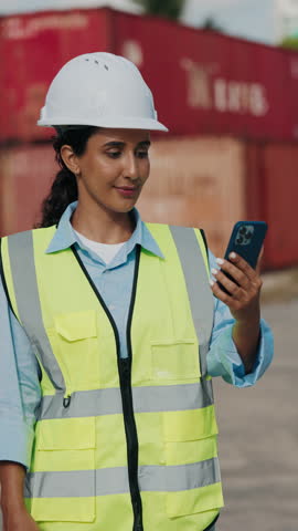Vertical Video. Beautiful Architect In Uniform On Video Conference, Signing I Miss You With Sign Language. Female Engineer In White Helmet At Warehouse Logistics Center Uses Gestures During Video Call
