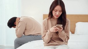 Asian couple on bed with digital disconnect causes relationship conflict, upset and worried, smartphone addiction strains romantic relationship, problem and unhappy, stress and trouble of couple. - Powered by Shutterstock - Get 15% off with code: PIKWIZARD15