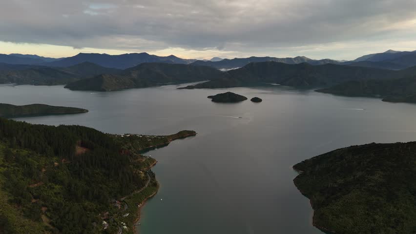 Panoramic aerial drone view of Cook Strait, separating North and South Islands of New Zealand, with rugged mountains and vast water under a cloudy sky. Epic landscape