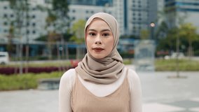Portrait of young Malaysian woman in hijab smiles to camera stands in city park. Pretty Muslim lady represents diversity modern lifestyle and female empowerment in town environment - Powered by Shutterstock - Get 15% off with code: PIKWIZARD15