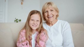 A 65-year-old woman and her 10-year-old granddaughter wave at the screen as they begin a video call. Positive interaction as part of continuous communication and mentorship. High quality 4k footage - Powered by Shutterstock - Get 15% off with code: PIKWIZARD15