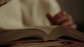 Close-up of warm light illuminating male hands turning book page, nestled atop stacked volumes in soft, muted library setting, creating intimate reading environment, selective focus, slow motion. - Powered by Shutterstock - Get 15% off with code: PIKWIZARD15
