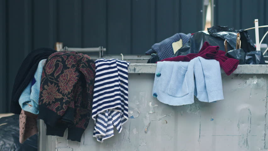 Abandoned clothes over, near and inside a dumpster in Sofia, Bulgaria.