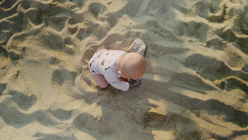 Young boy playing joyfully in soft golden sand on a sunny beach, exploring textures and shapes, creating a playful atmosphere of childhood innocence and adventure