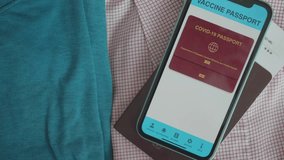 A close-up view of a digital COVID-19 vaccine passport displayed on a smartphone next to a folded shirt. The passport includes a QR code and a "vaccinated" confirmation, symbolizing health compliance  - Powered by Shutterstock - Get 15% off with code: PIKWIZARD15