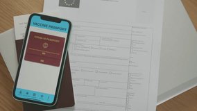 A smartphone displaying a digital COVID-19 vaccination passport alongside printed documents. The passport features a QR code and confirmation of vaccination status, symbolizing the importance of vacci - Powered by Shutterstock - Get 15% off with code: PIKWIZARD15