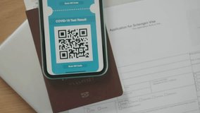 A smartphone displaying a digital COVID test result QR code, placed alongside a passport and a visa application form. This image highlights essential travel documents in the context of health safety. - Powered by Shutterstock - Get 15% off with code: PIKWIZARD15
