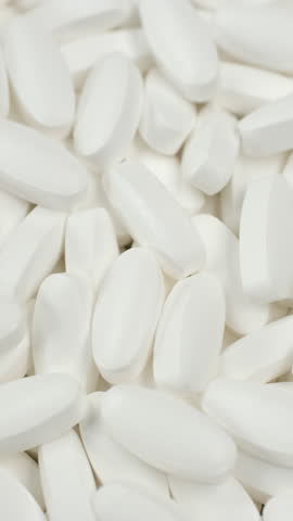 Zoom frame Heap of white pills, rotate. Production of pharmaceuticals and drugs