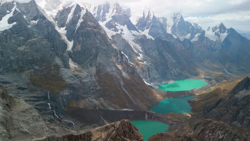 Spectacular aerial panorama reveals the iconic Tres Lagunas - Jurau, Solteracocha, and Azulcocha - amidst the majestic Cordillera Huayhuash peaks in Peru.