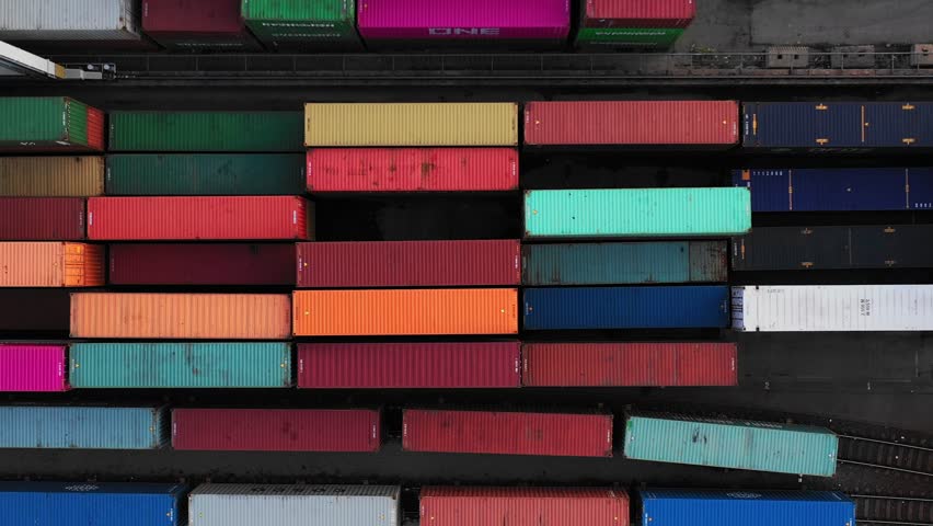 Flying above industrial railroad station with cargo trains and freight containers. Railroads and shipping container trains.