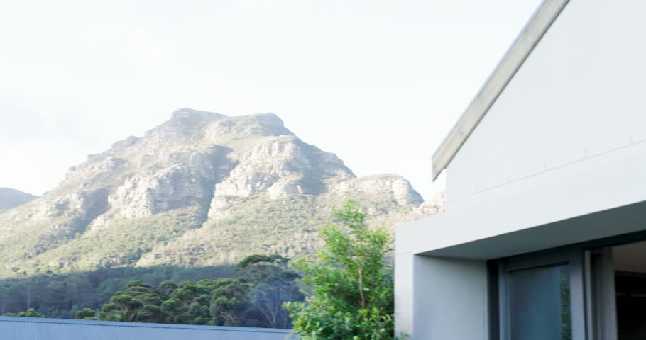 Sitting at sliding glass door opening woman in olive-green loungewear gazing at mountain copy space. Residential, tranquility, modernity, leisure, minimalism, harmony, nature