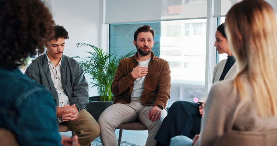 Man, talking and circle of people for counseling, sharing story and addiction recovery. Person, discussion and community kindness, therapy support and awareness of mental health at psychology session