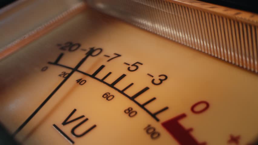 Analog dial indicator of audio signal level amplifier. Vintage arrow moves with sound level. Round classic volume indicator with yellow backlight, VU meters. Close-up of old measuring dB decibels