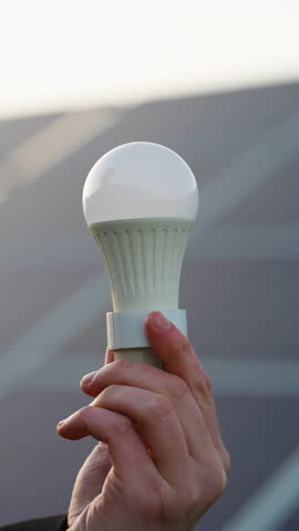 Hand holding a led light bulb powered by solar panels