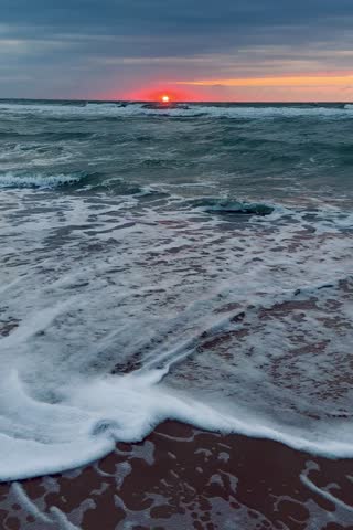 Beautiful sunset over the North sea, scenic clouds, splashing waves. 