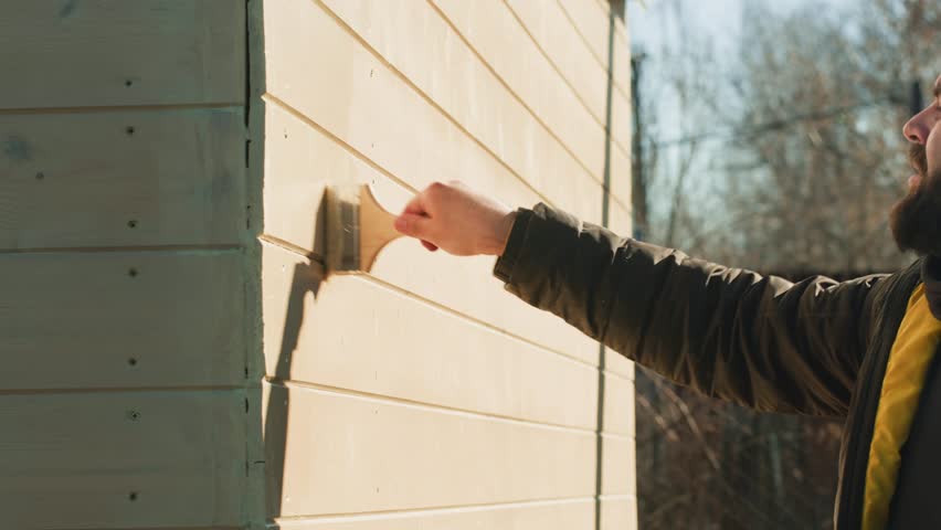 Painting house outdoor, Close up of painter hand holding brush painting white wall. Home painting and decorating concept, small building summer house for sale or real estate.