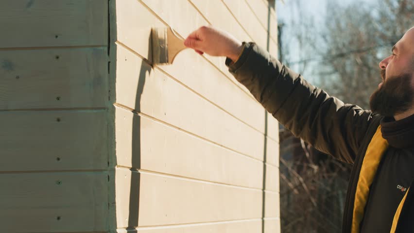 Painting house outdoor, Close up of painter hand holding brush painting white wall. Home painting and decorating concept, small building summer house for sale or real estate.