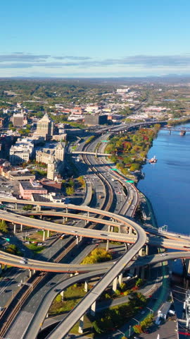 Traffic on the overpasses on the banks of the Hudson River. Aerial view of the Interstate 787 and South Mall Arterial interchange in downtown Albany. Vertical video.