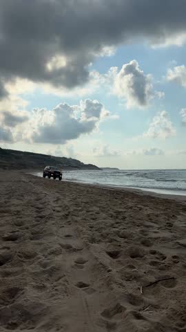 SUV Driving on the Beach

A black SUV drives along a sandy beach under a cloudy sky, leaving deep tire tracks behind.
