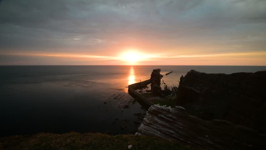 Sunset mood at the rock "Tall Anna" with flying birds. View of the rock "Lange Anna" by sunset in summer, Helgoland, Schleswig-Holstein, Germany. Northern gannets flying by Helgoland.
