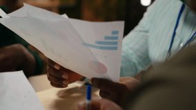Close up of diverse staff collaborating on data forecasting and analysis, exchanging documents late in the office. Updating stakeholders with predictions and other business intel. Camera B. - Powered by Shutterstock - Get 15% off with code: PIKWIZARD15