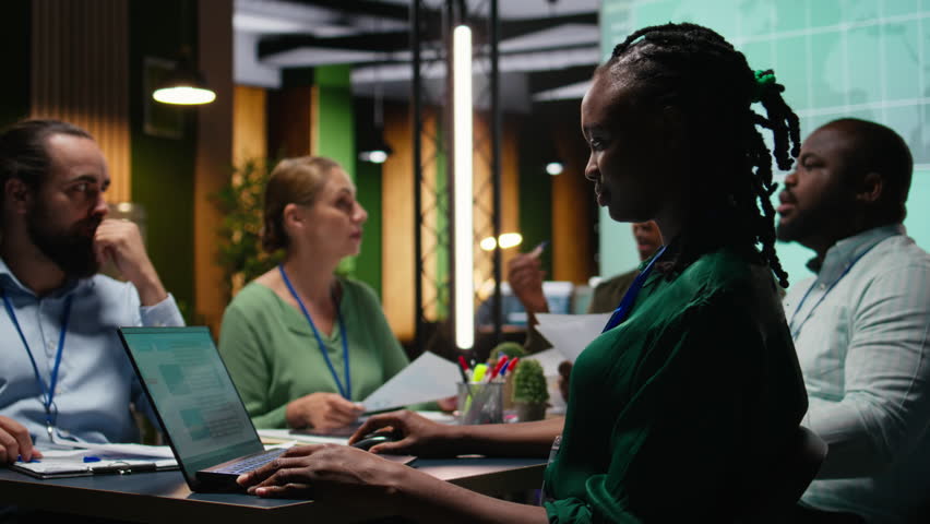 Diverse administrative team attending briefing conference at night to verify updates on regulatory changes or industry standards. Business professionals reviewing all data analysis. Camera A.