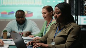 African american analyst and colleagues examining annual data reporting in a firm meeting at night, reviewing insight on laptop to facilitate global business development. Work team. Camera B. - Powered by Shutterstock - Get 15% off with code: PIKWIZARD15