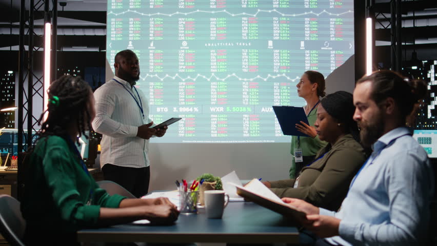 Diverse business associates reviewing performance metrics data within the multinational company. Conducting analytics for general overview, professional development after hours. Camera A.