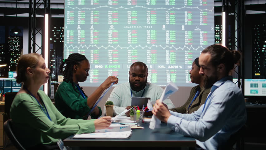 Diverse employees discuss project details and forecast information at night, ensuring business objectives accomplishment during late meeting after hours. Share proposals. Camera A.