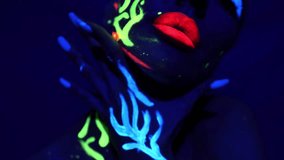 Portrait of a young girl on a dark background painted with fluorescent colors. A woman with glowing makeup poses for the camera. - Powered by Shutterstock - Get 15% off with code: PIKWIZARD15