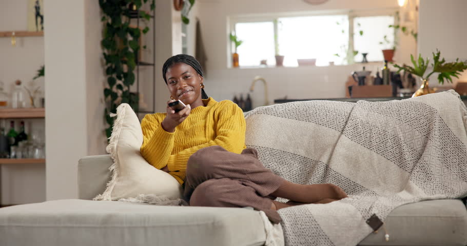 Black woman, remote control and smile in living room for watching tv, movies or streaming in home. Gen z girl, relax and choice in house for comedy, film or television on couch in apartment lounge