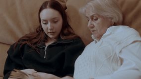 Loving grandmother sharing reading moment with young granddaughter, sitting comfortably on living room sofa, connecting through storytelling and family bond - Powered by Shutterstock - Get 15% off with code: PIKWIZARD15