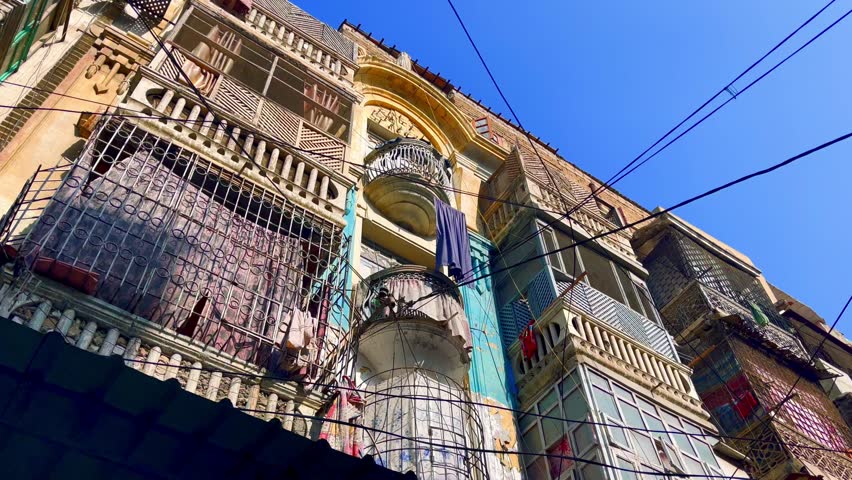 Low angle view of a heritage building with balconies and clothes hanging, showcasing the architectural style of Sadar, Karachi
