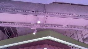 Interior ceiling with exposed ductwork and track spotlights casting a soft pink–purple glow over a modern commercial space, highlighting contemporary lighting fixtures. - Powered by Shutterstock - Get 15% off with code: PIKWIZARD15
