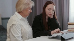 Elderly grandmother providing educational guidance, supporting teenage granddaughter while studying together using digital tablet in comfortable home environment - Powered by Shutterstock - Get 15% off with code: PIKWIZARD15