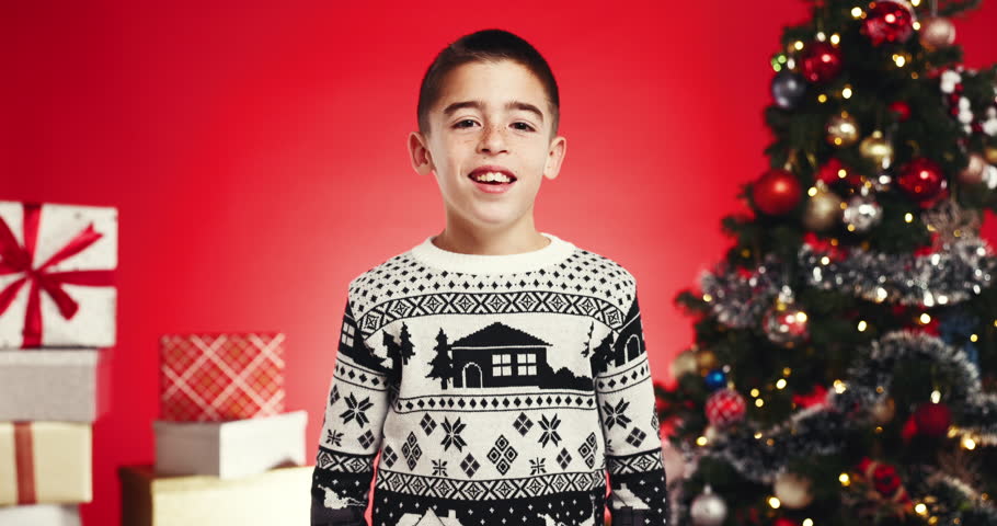 Studio, face and child with smile, christmas or excited for festive season, arms crossed or holiday. Red background, confident and boy with Xmas sweater, December and happy for celebration in USA