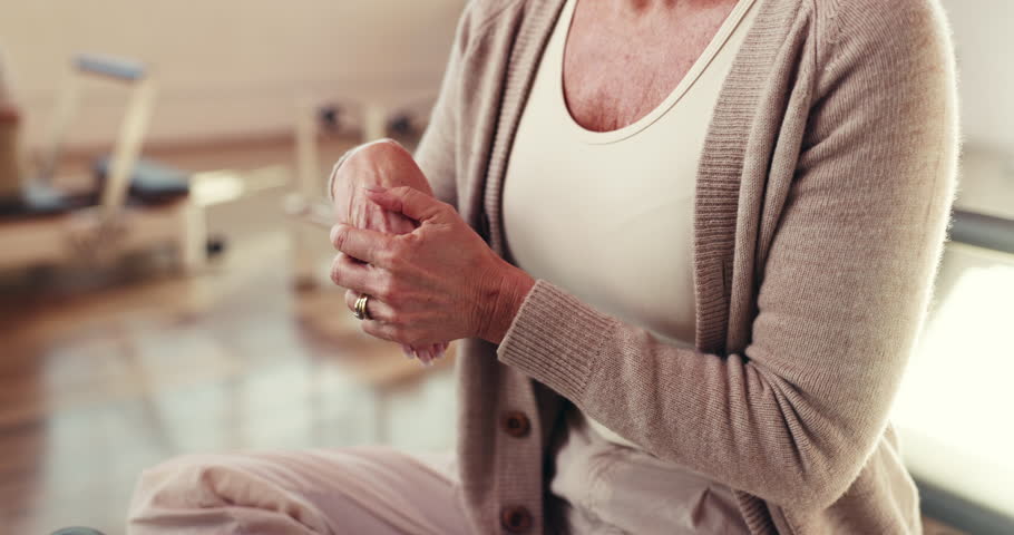 Pilates, hands and woman stretching wrist for fitness, health or arthritis relief in gym class. Senior person, fingers or warm up for exercise preparation, physical therapy or practice rehabilitation