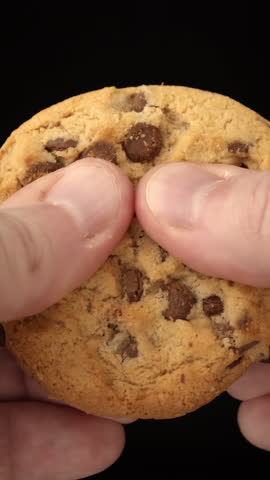 Cookie tearing apart in hands with visible chocolate chunks and fine detail, isolated for use in food-centered promo compositions