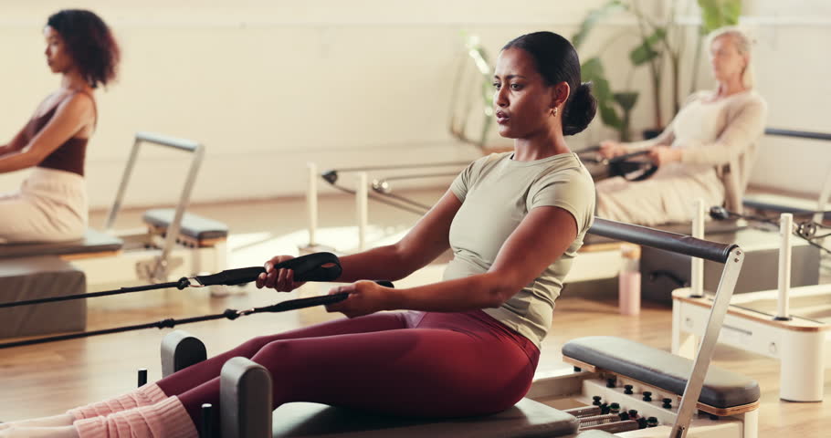Woman, pilates and rowing workout with reformer, breathe or machine for routine at fitness club. Person, gym equipment and resistance band for strength training, muscle or exercise at wellness studio