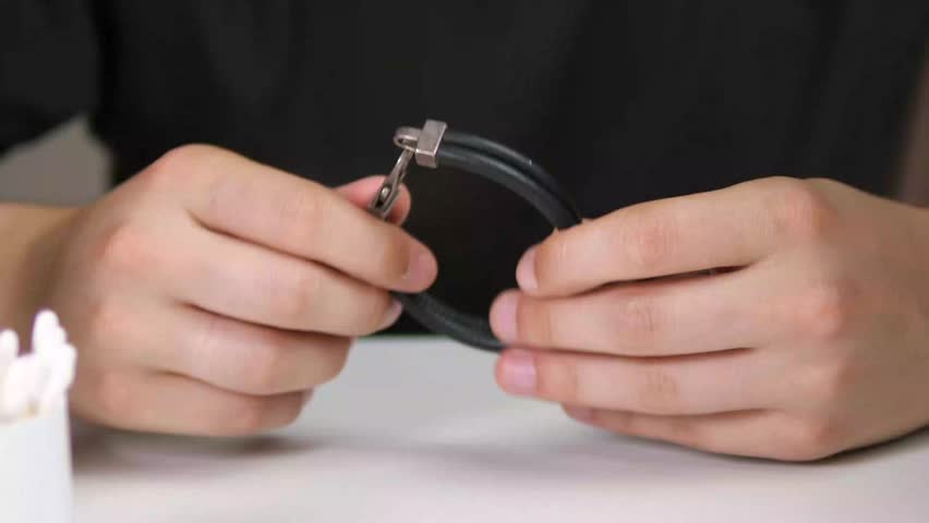 Leather bracelet with a clasp made of precious metals in the hands of a man. Brutal male jewelry. 