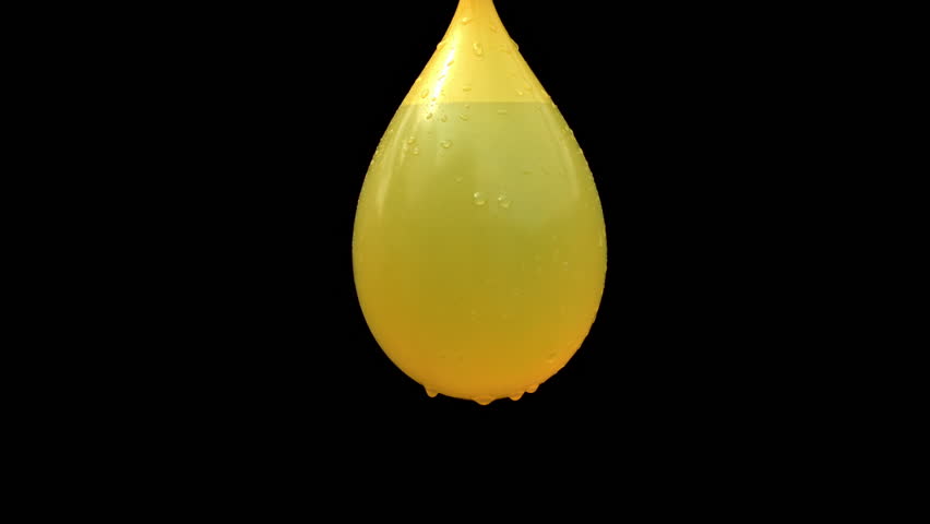 Close-up slow motion of a knife slicing through a yellow water balloon, causing a dramatic splash against a black background - Powered by Shutterstock - Get 15% off with code: PIKWIZARD15