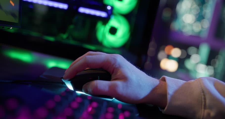 Close Up of Gamer’s Hands Rapidly Pressing Movement Keys on a Glowing RGB Computer Keyboard During Intense Gameplay at Home in a Dark Room. Anonymous Player Playing an Online Shooter Video Game