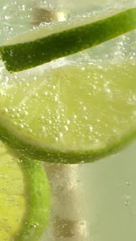 	
Straw stirs limes and ice cubes in sparkling water.	
