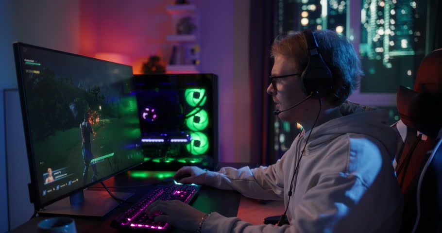 Portrait of a Young Caucasian Man Focused on a Gaming Tournament, Playing Fantasy Shooter Video Game Online while Sitting at Home in His Neon-lit Room. Smooth Arc Shot