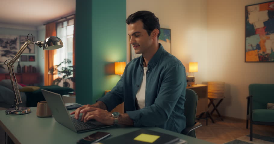 Close Up of a Young Multiethnic Man Opening Up a Laptop and Starting to Work at Home. Male Sitting Behind a Table in Living Room, Using Computer. Dynamic Robot Camera Footage