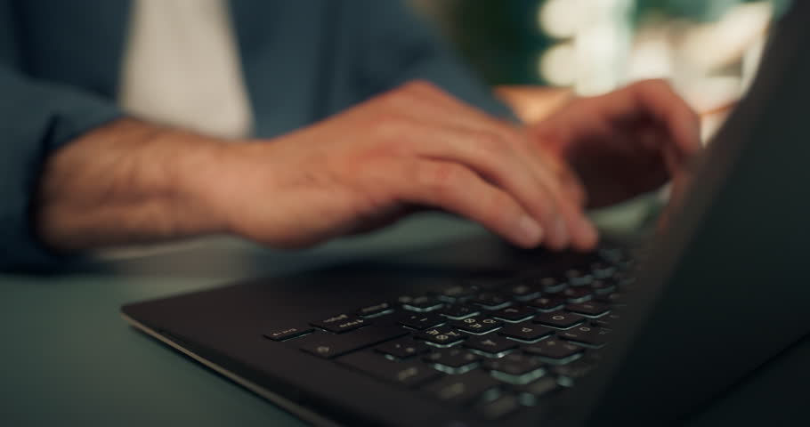 Middle Eastern Young Man Working Remotely from Home, Sitting in a Living Room Behind a Desk and Using a Computer. Male is Drinking from a Cup while Browsing Reports a Laptop. Creative Arc Footage