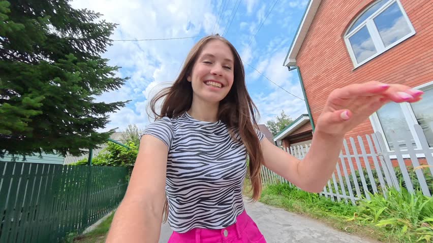 Video selfie of a young happy girl smiling riding a bike. Shot on an action camera.