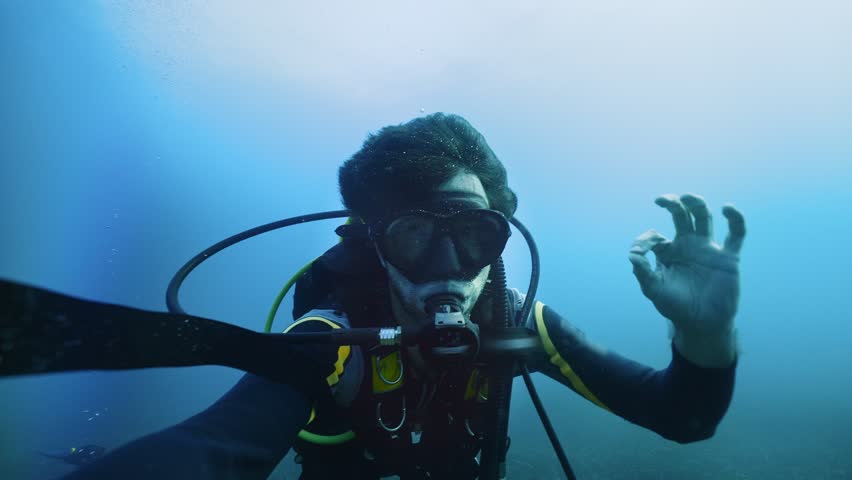 Scuba diver doing safety OK underwater sign, enjoying deep diving in the ocean