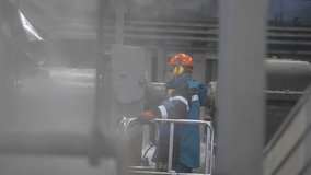 Employee observes massive machinery from safe high walkway. Process beneath looks complex automated ongoing under experienced guidance - Powered by Shutterstock - Get 15% off with code: PIKWIZARD15