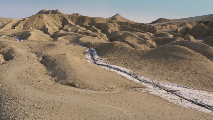 A long-haired man dressed in a white robe, descending the sandy hills of the Judean Desert. Tracking shot